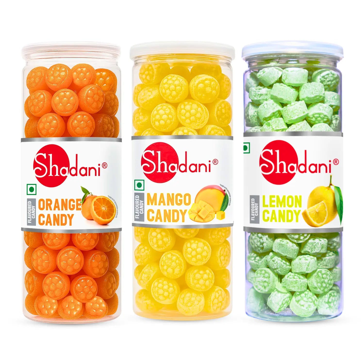 Three clear plastic jars of Shadani candies on a white background: orange round candies labeled Orange Candy, yellow round candies labeled Mango Candy, and light green cube-shaped candies labeled Lemon Candy.