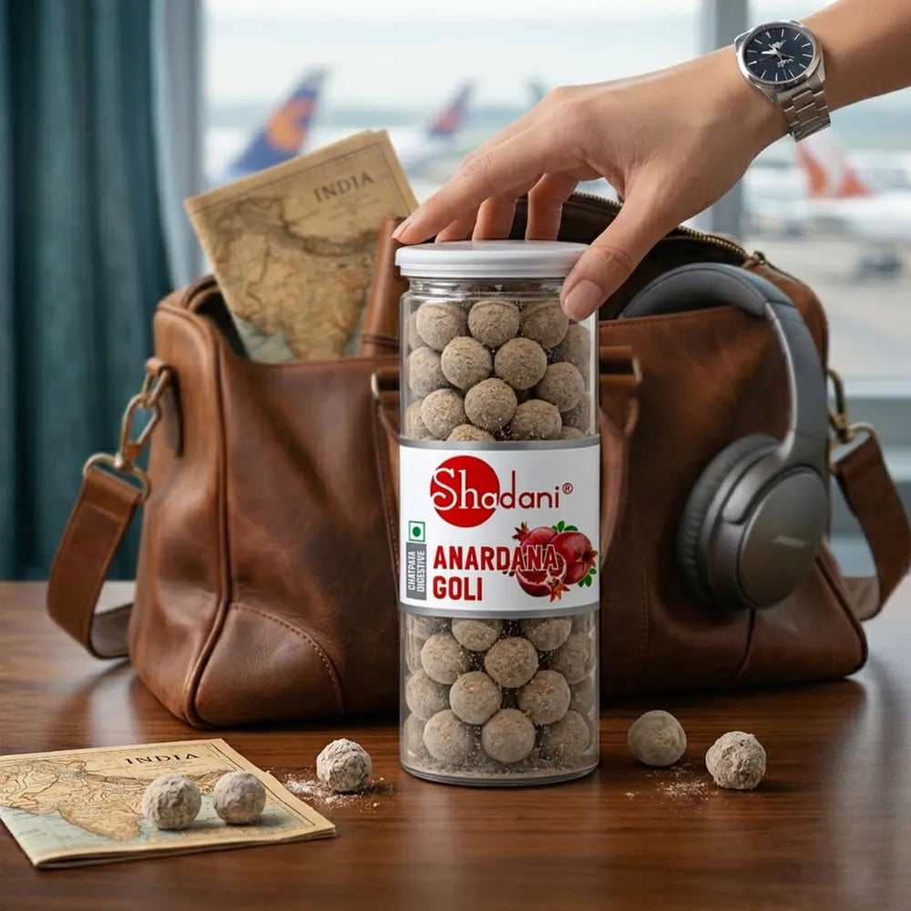 Shadani Anardana Goli jar with a hand holding it, placed on a table with a brown bag and maps in the background.