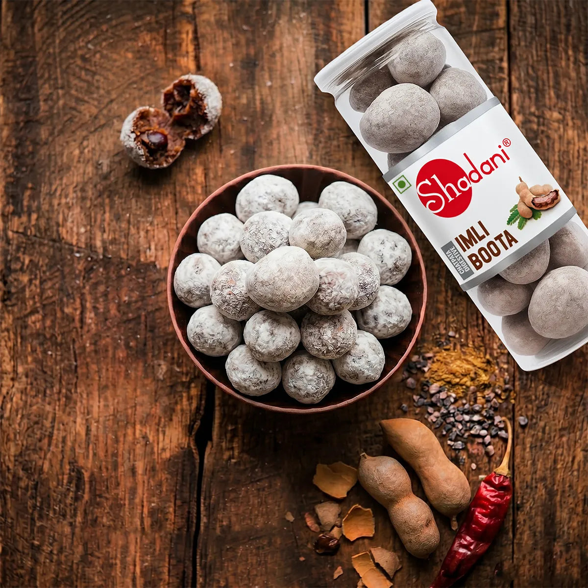 Shadani Imli Bota on a wooden surface with a bowl of the product and packaging.