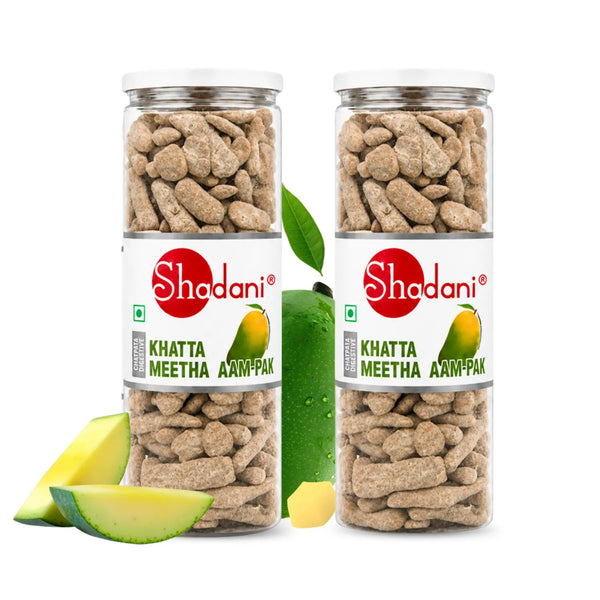 Two clear plastic jars of Shodani Khatta Meetha Aam-Pak (mango pickle) on a white background, styled with fresh mango slices and a whole mango.