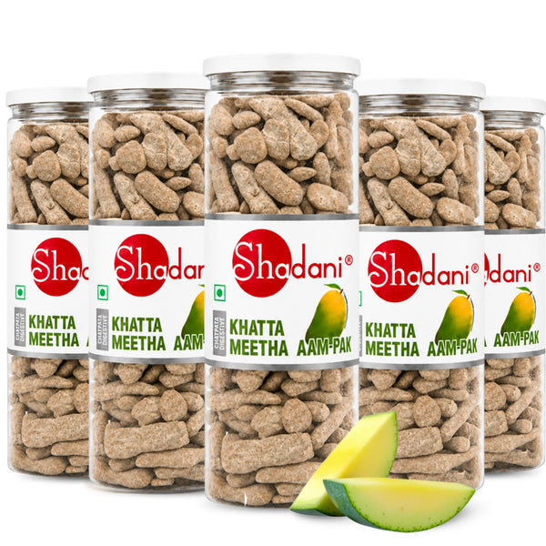 Five clear plastic jars of Shadani Khatta Meetha Aam Pakka tea biscuits arranged in a group on a white background, with two green mango slices in front. The jars have white lids and white labels with a prominent red Shadani logo.