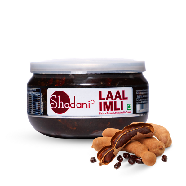 A jar of Shadani Laal Imli candy with the label visible, alongside pieces of tamarind fruit and seeds displayed in front.