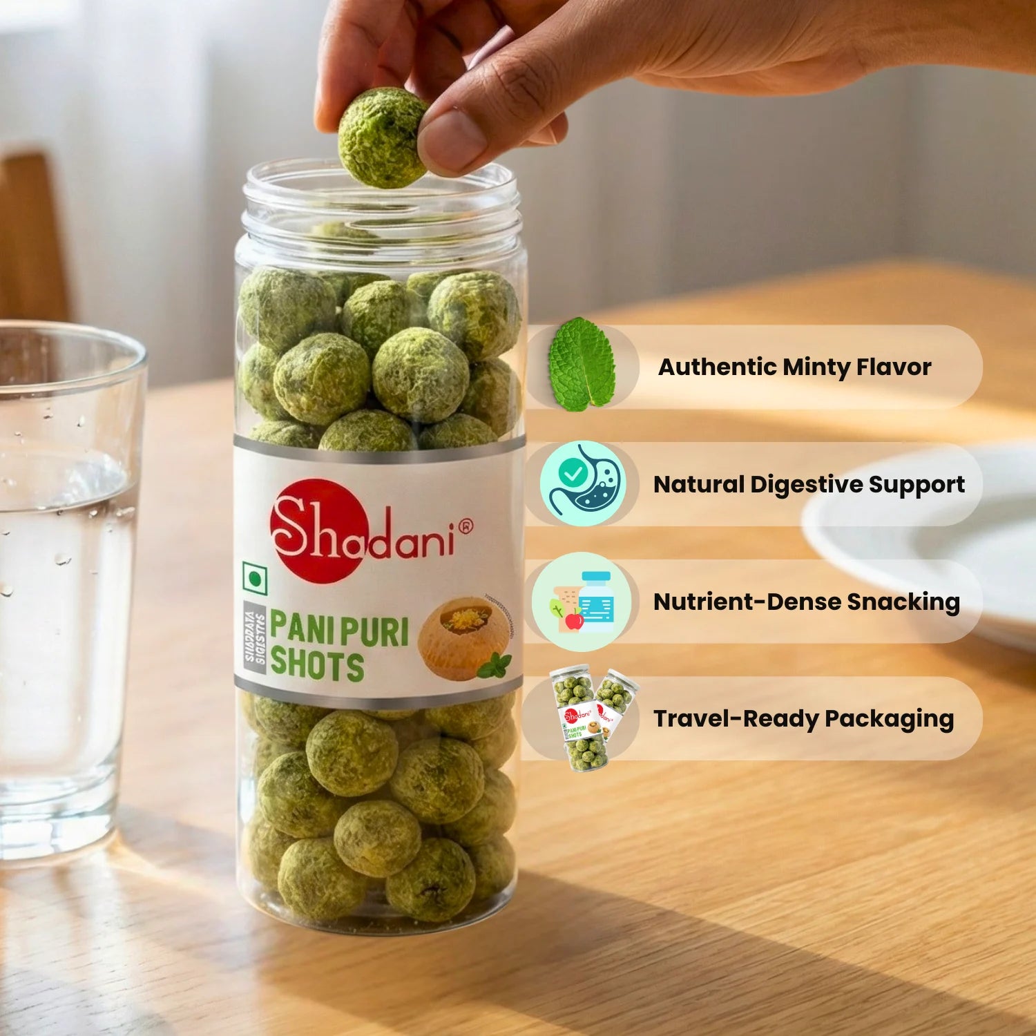 Shadani Pani Puri Shots in a glass jar on a wooden surface with a hand holding a shot.