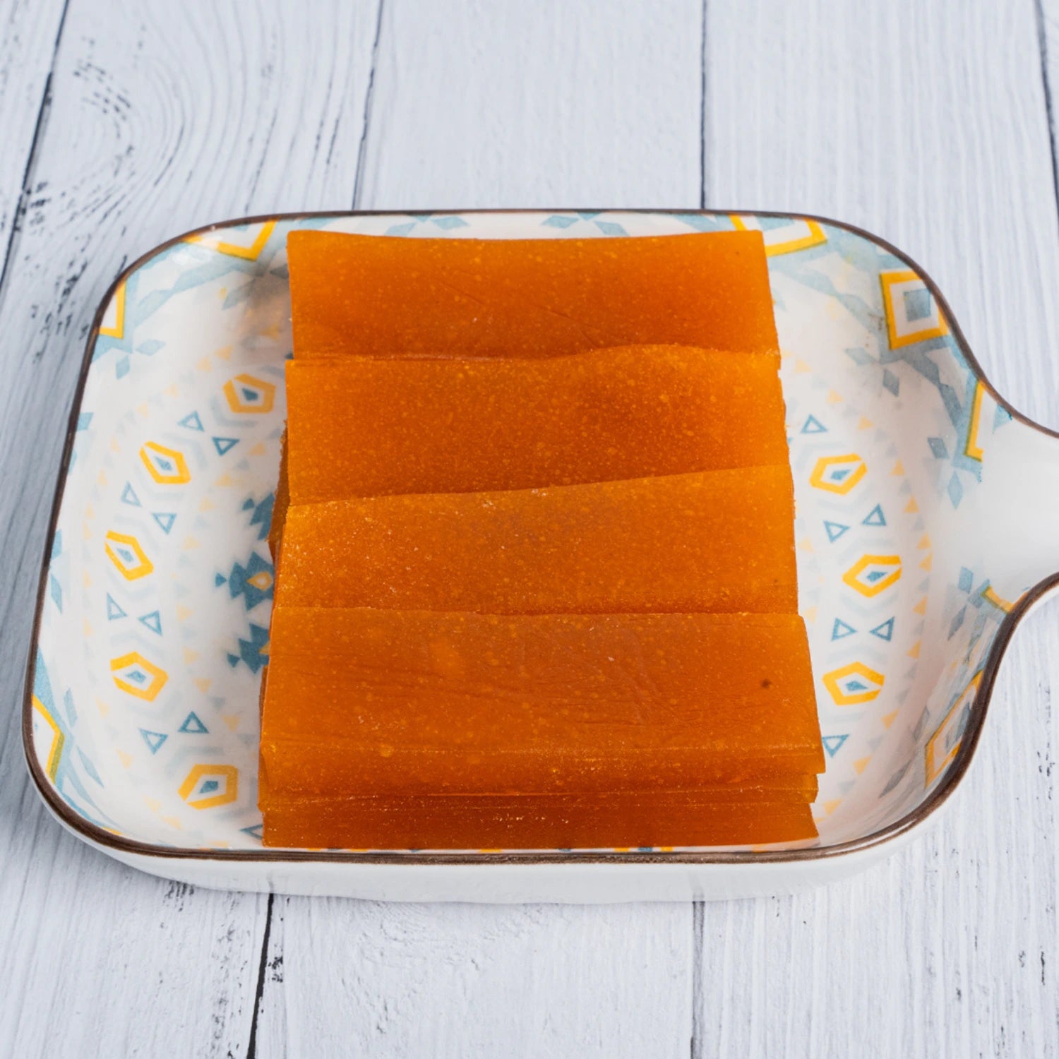 Sliced shadani aampapad on a decorative ceramic plate with a white wooden background