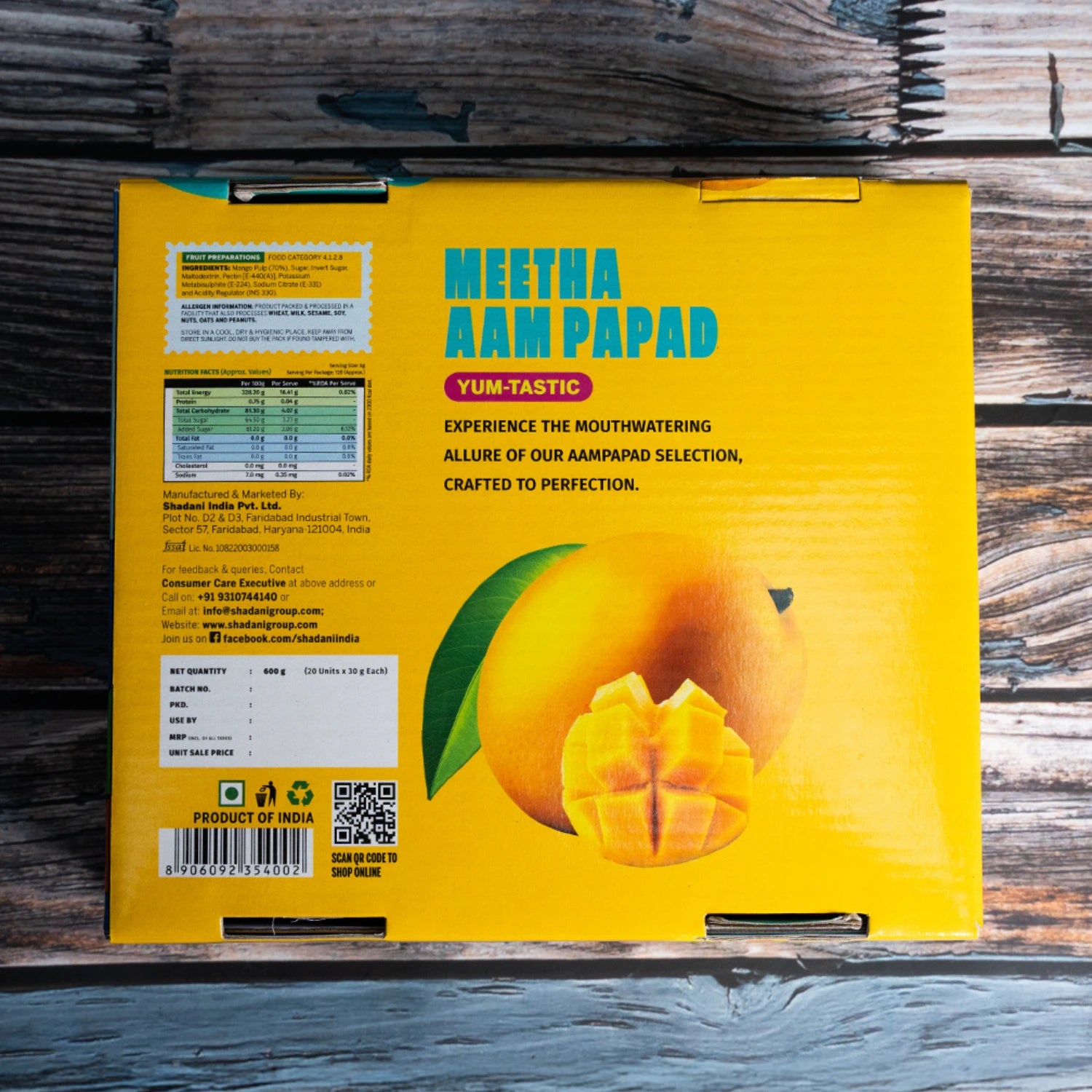 Yellow packaging of Shadani Meetha Aampapad with a mango illustration on a wooden surface