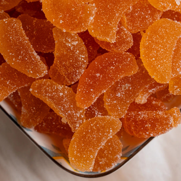 Close-up of orange gummy bears in a glass bowl.