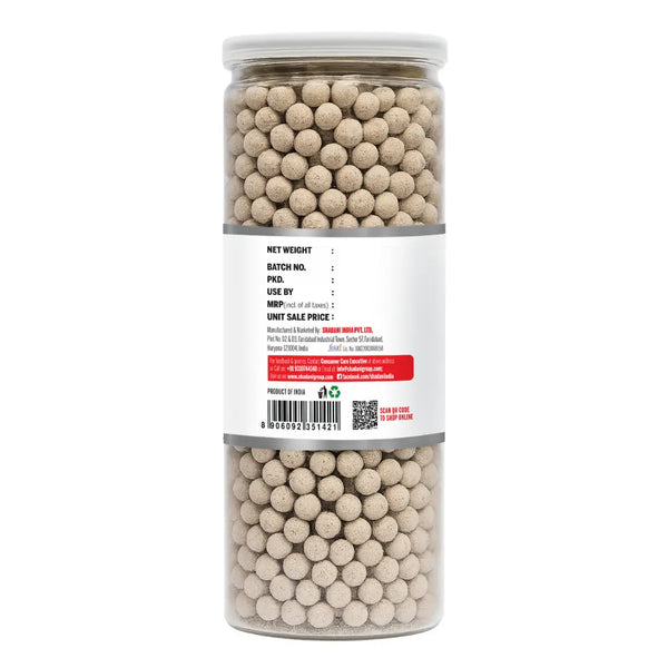 Jar of beige spherical objects Jeera goli with a label on a white background