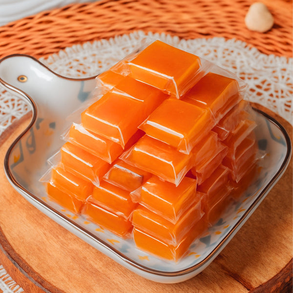 Stack of orange jelly cubes on a decorative plate with a woven background