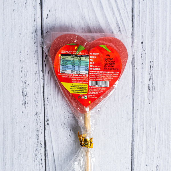 Packaged lollipop with a red label on a white wooden surface