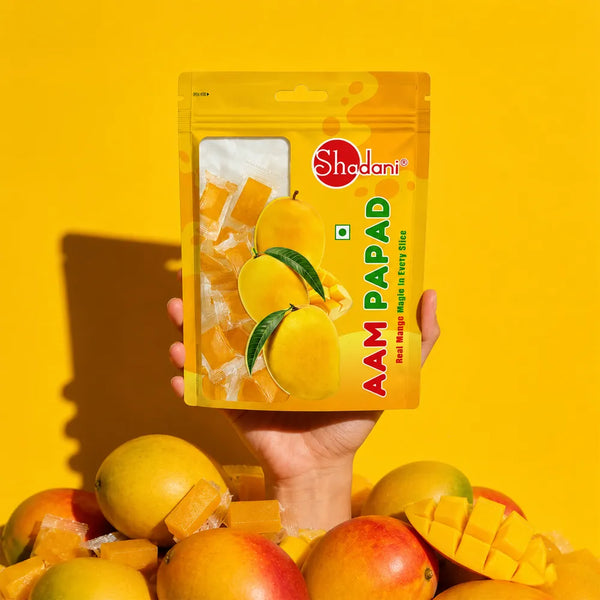 Shadani Aam papad pouch in one hand that poping our from the collage of real mango 